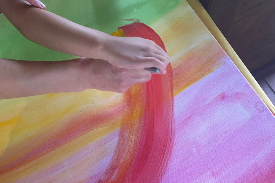 Zwei Hände malen gemeinsam ein Bild beim Sommerfest Projekt Regenbogen